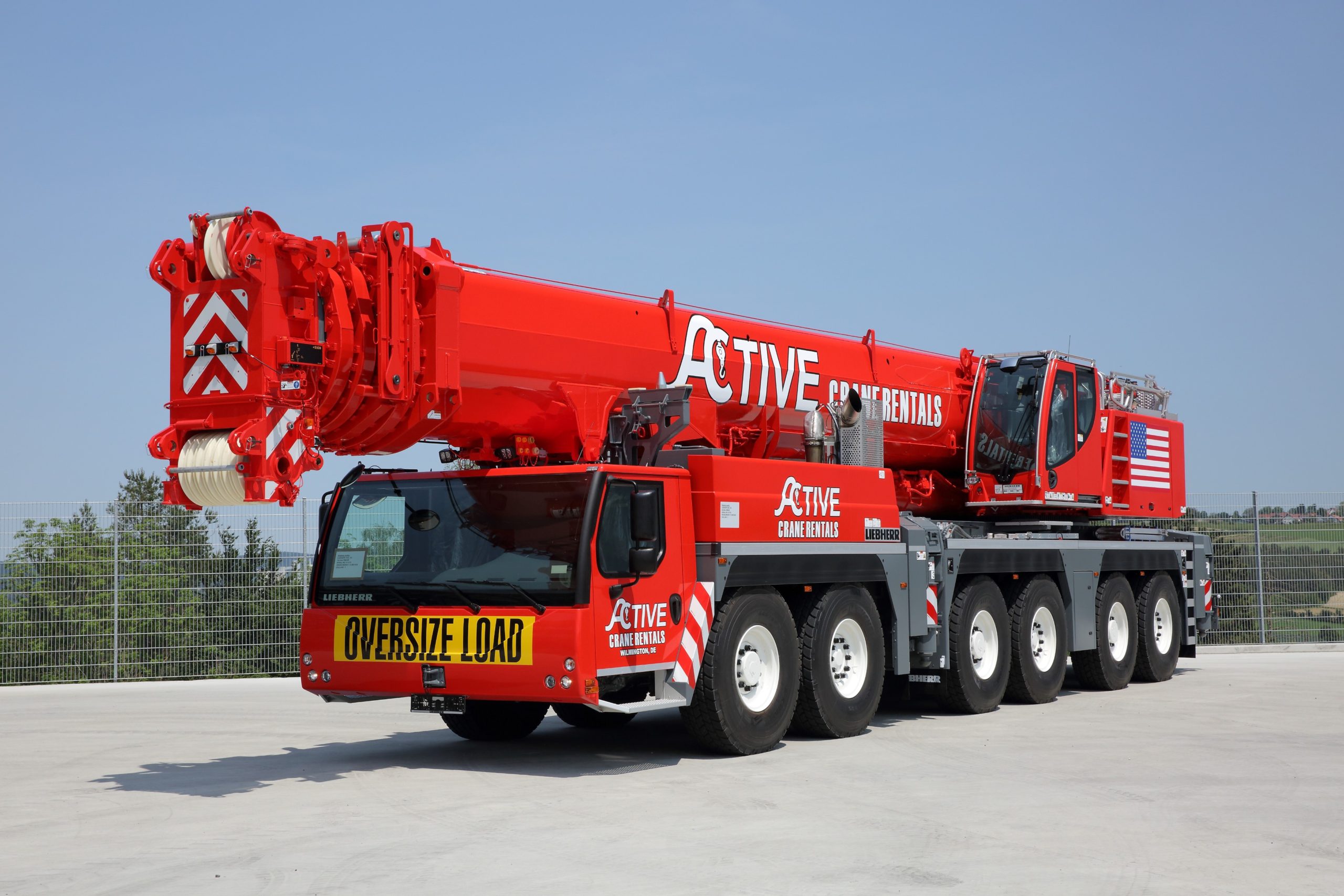 Red mobile crane with oversized load banner on front
